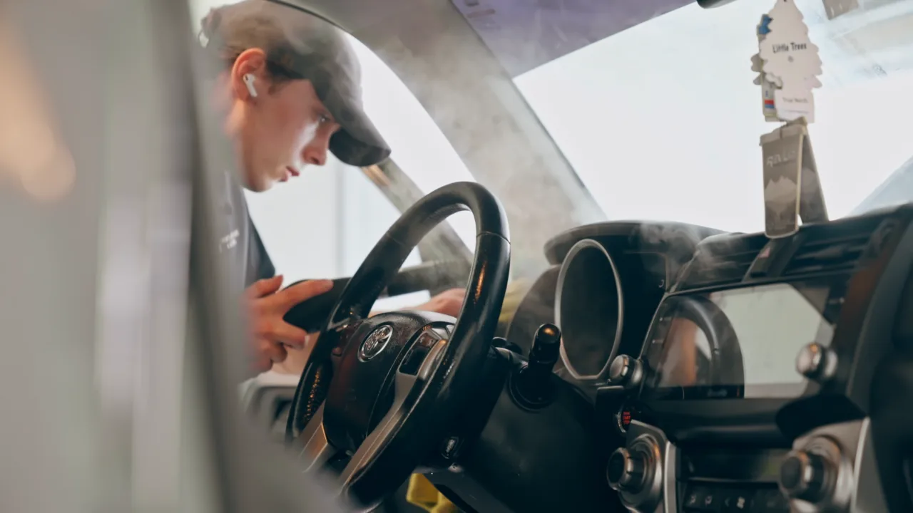 Steam cleaning the dashboard and steering wheel of an SUV
